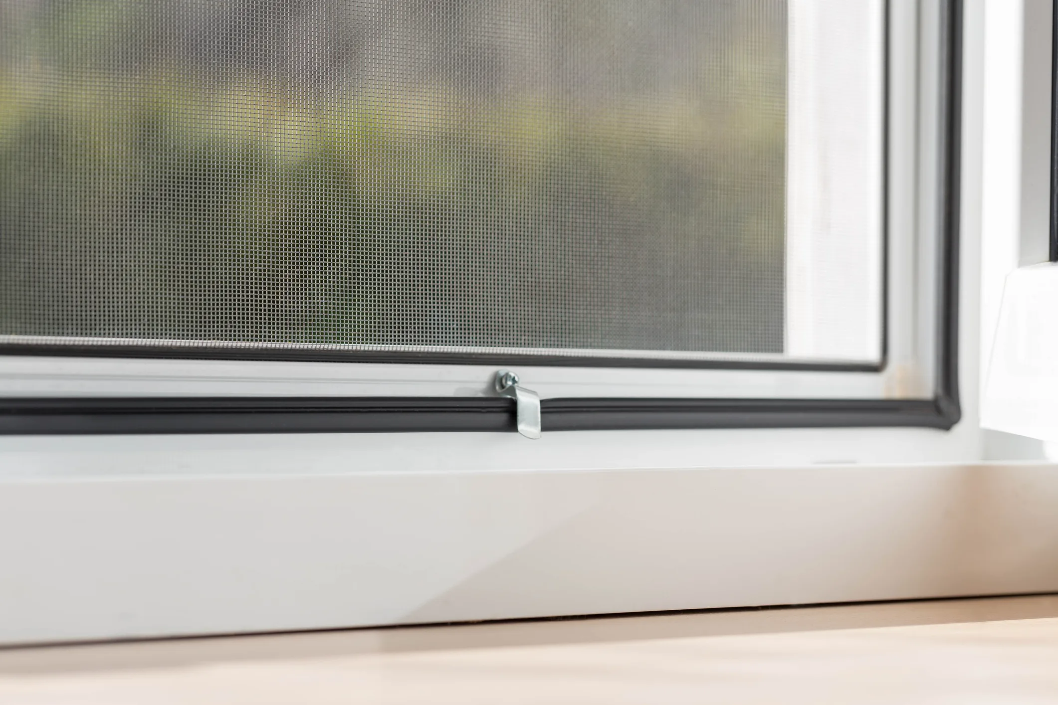 Detalle de mosquitera cerrada integrada en una ventana blanca